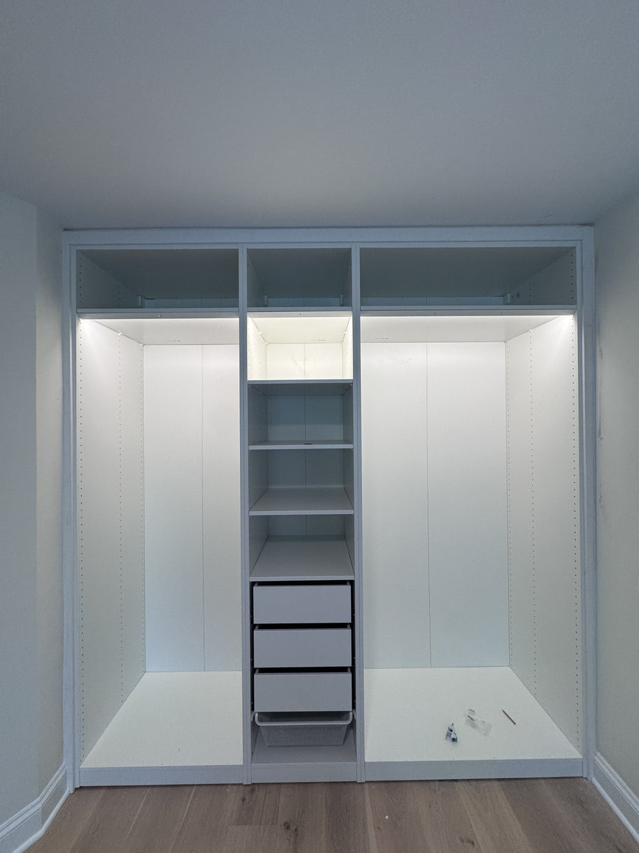 Real ModuCloset installation — illuminated closet interior with hanging storage, shelves and drawers.