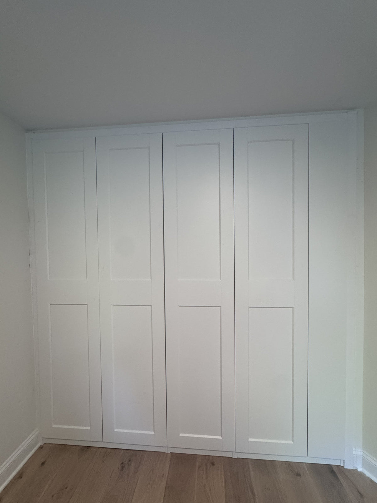 Real ModuCloset installation — white built-in closet with closed Shaker doors, frontal view.
