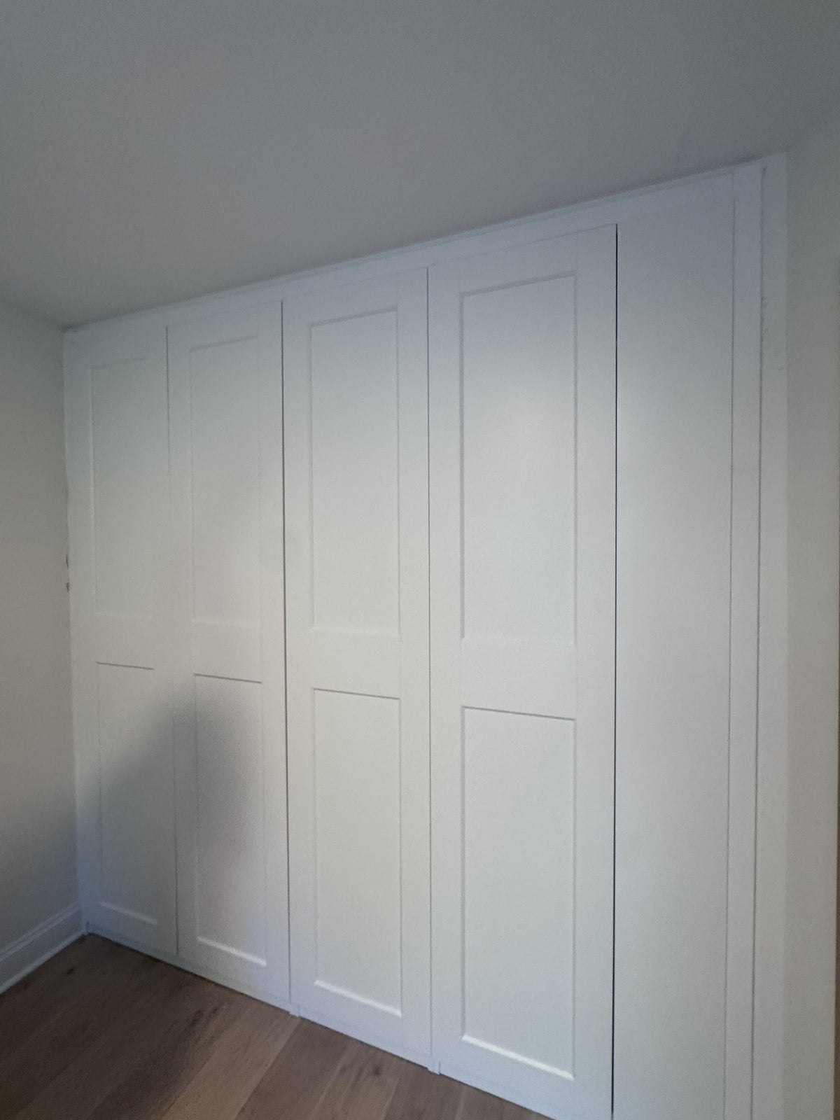 Real ModuCloset installation — alternate angle of finished white closet with closed Shaker doors.