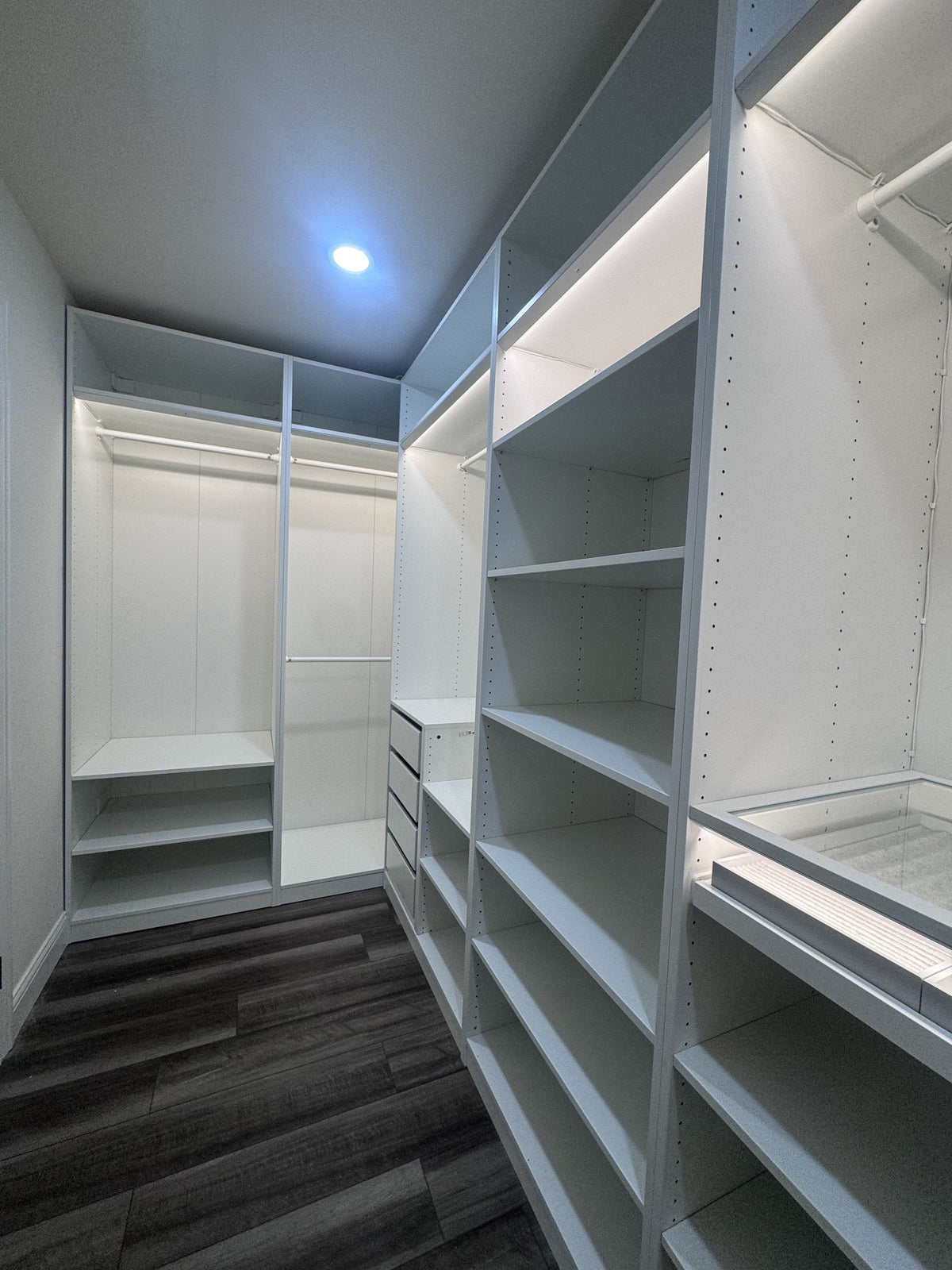 Real ModuCloset installation — illuminated hanging storage, shelving and drawer arrangement in the walk-in closet.