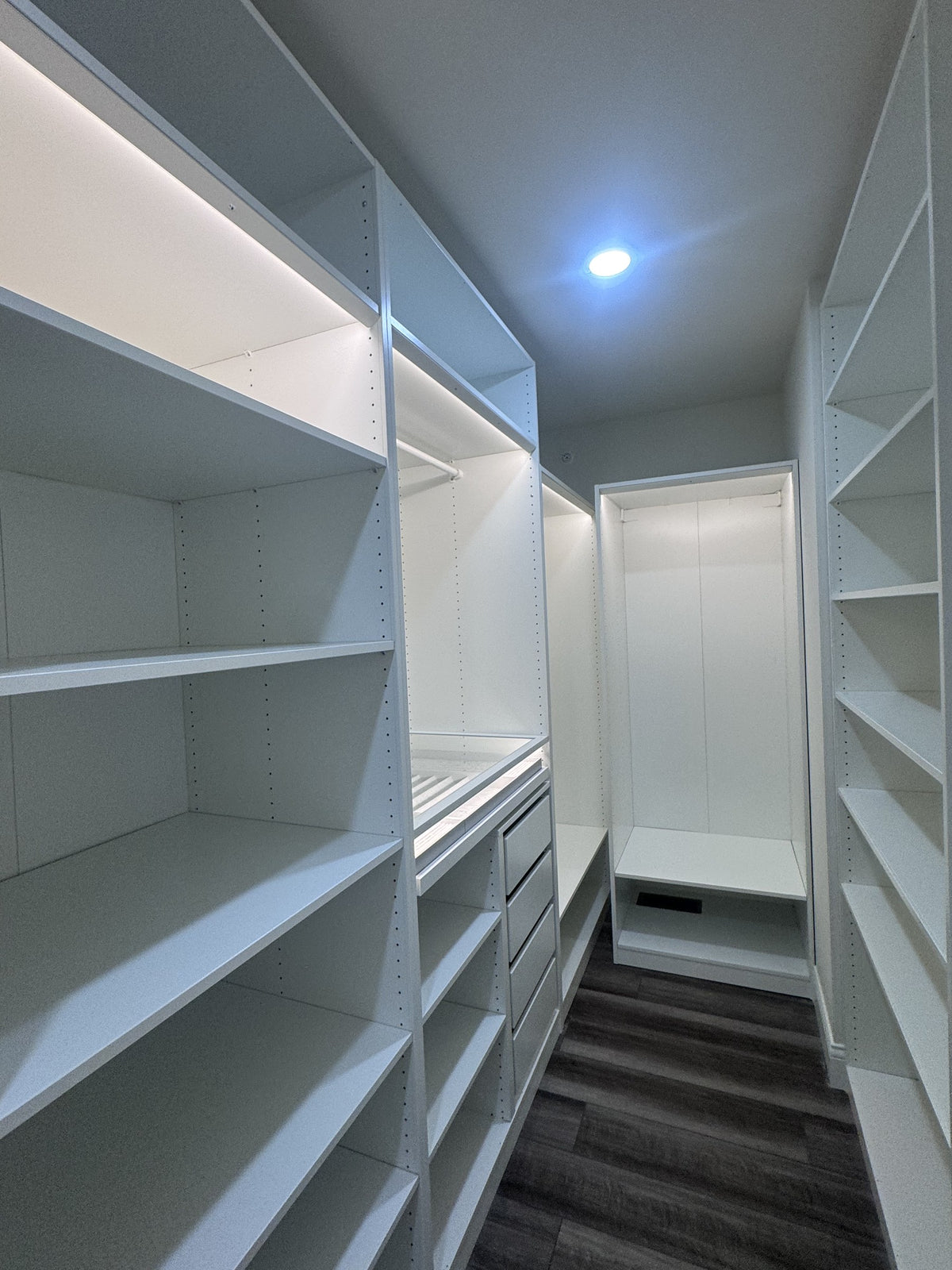 Real ModuCloset installation — aisle view with shelving and illuminated hanging bays.