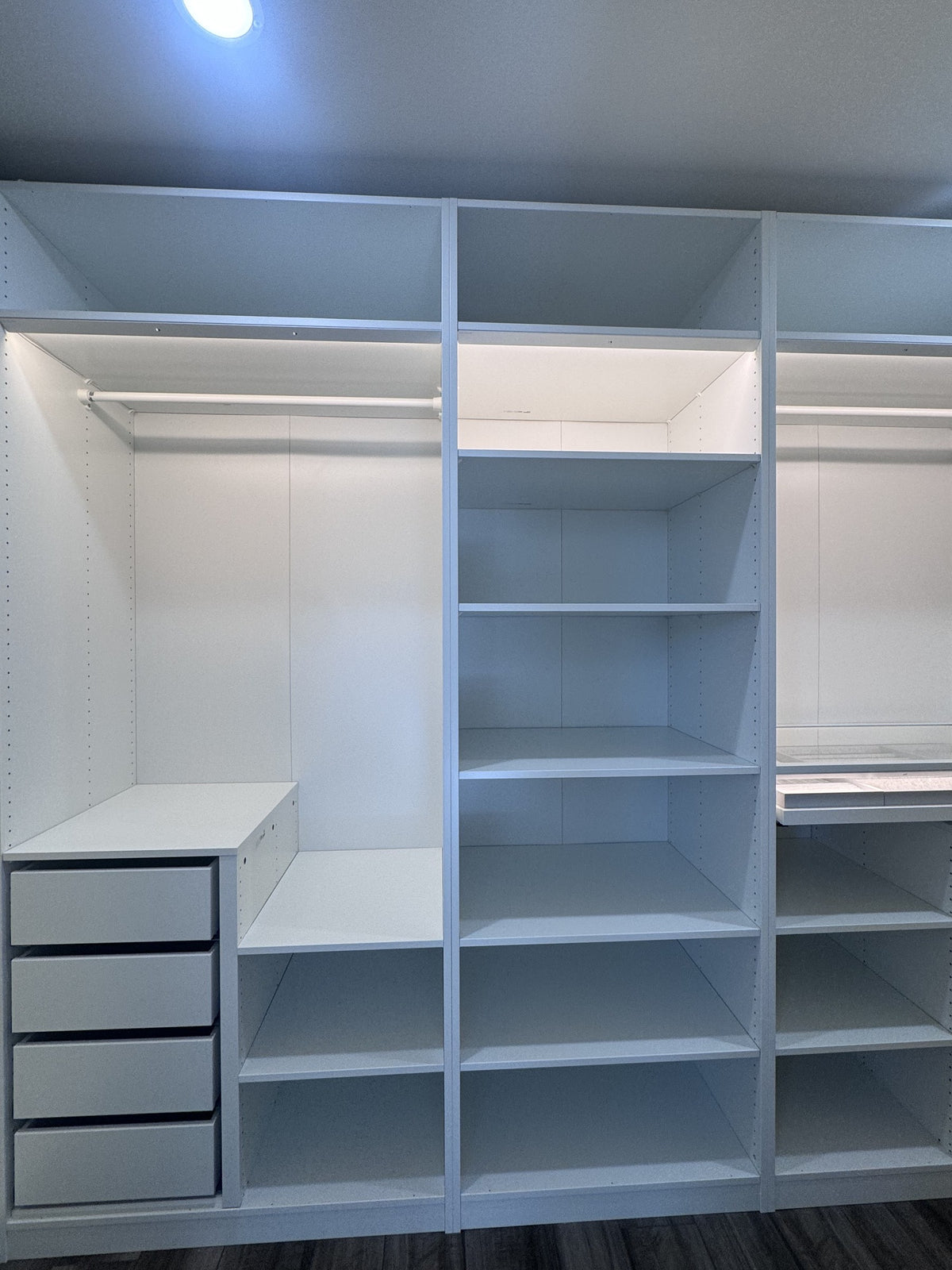 Real ModuCloset installation — shelf tower between illuminated hanging bays.